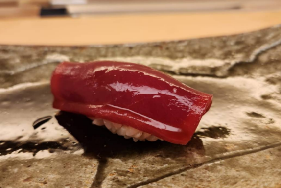A guest eating nigiri sushi by hand at a Japanese sushi counter, following traditional etiquette