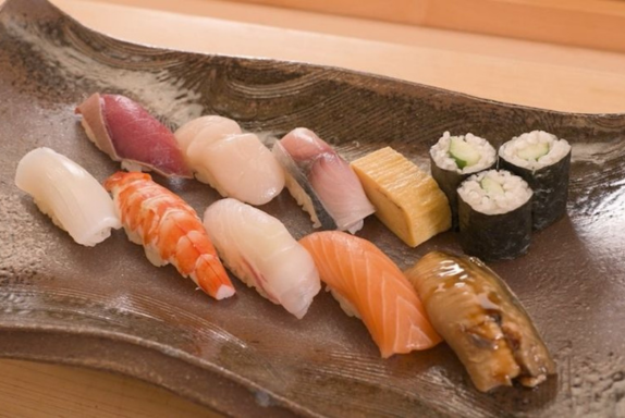 A professional sushi chef carefully forming nigiri sushi during an omakase course in Fukuoka