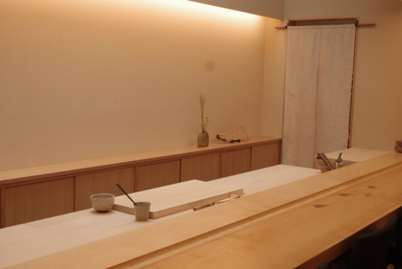 The intimate atmosphere of an authentic sushi counter with wooden bar and warm lighting in Japan